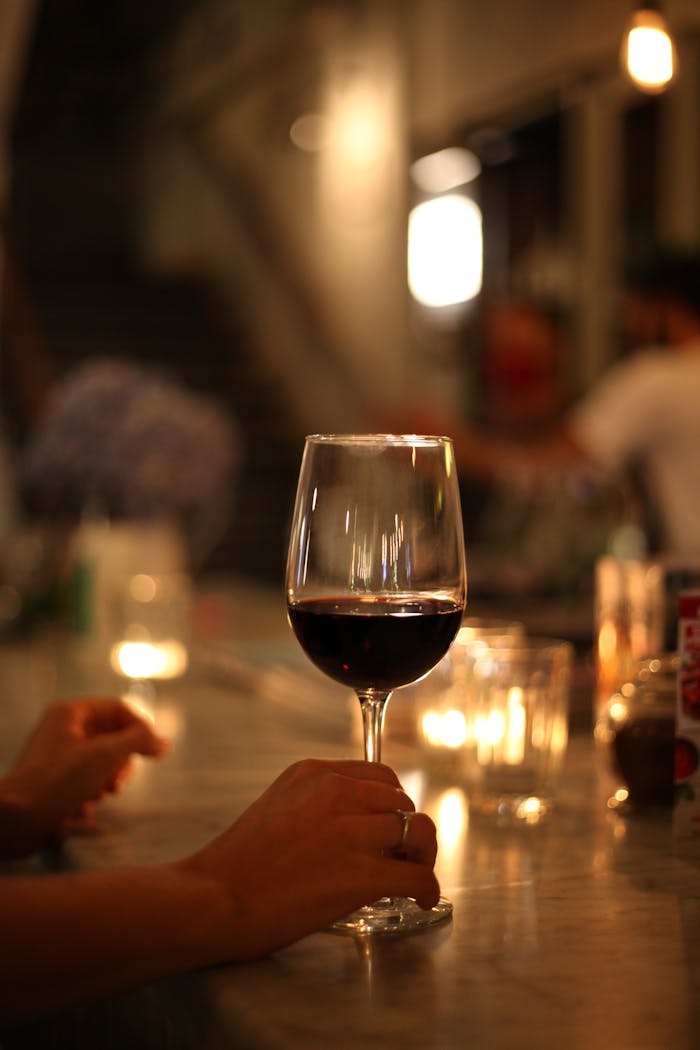 Enjoy a sophisticated evening with a glass of red wine in a cozy, dimly lit setting.